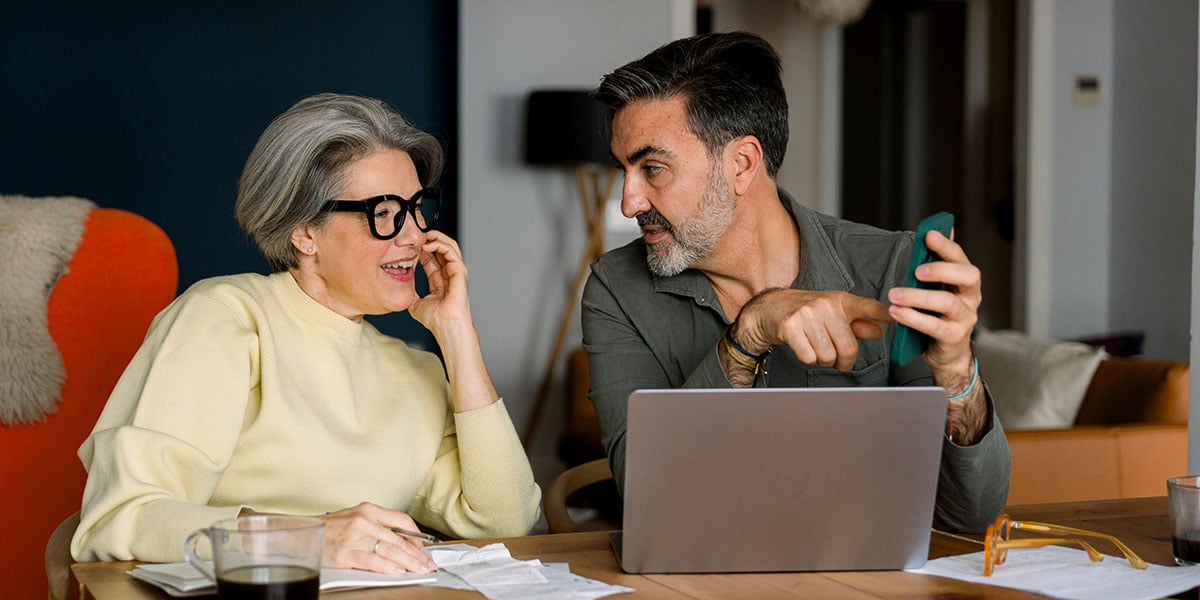 Couple discussing finances next to a laptop